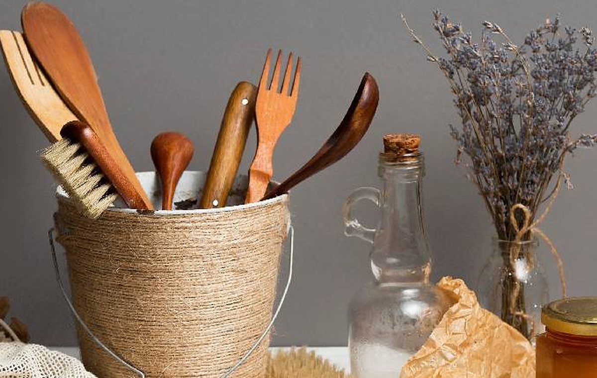 Wooden kitchen utensils in a basket with jars on a counter